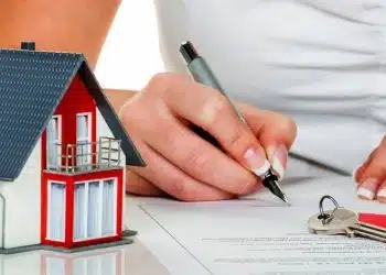 a woman signs a contract for a house with a real estate agent.